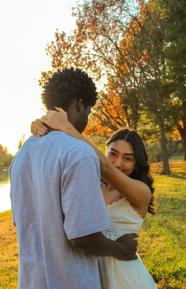 Couple embracing under autumn trees by a lake