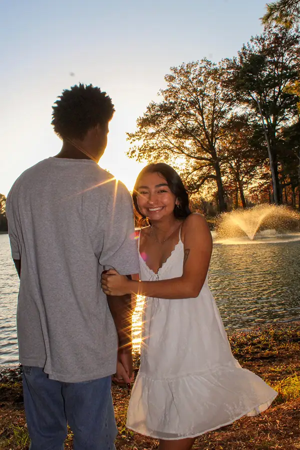 Couple standing by a lake fountain at sunset
