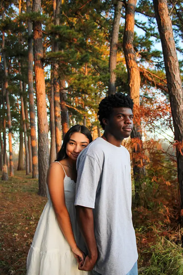 Couple leaning together among tall pine trees