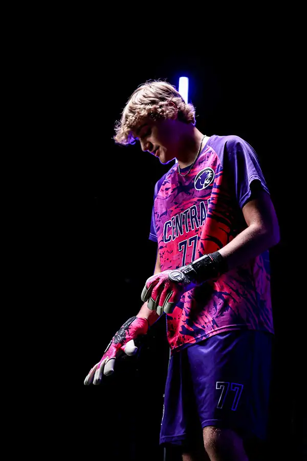 Young man in a purple jersey under a single spotlight on black