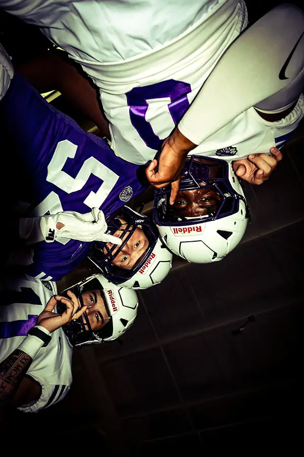 Football players in purple helmets looking down into the camera
