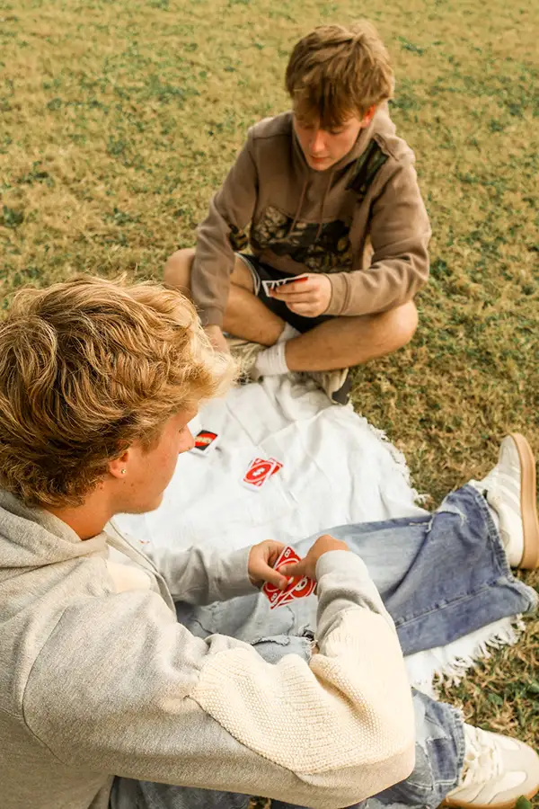 Two friends sitting in the grass looking at photos