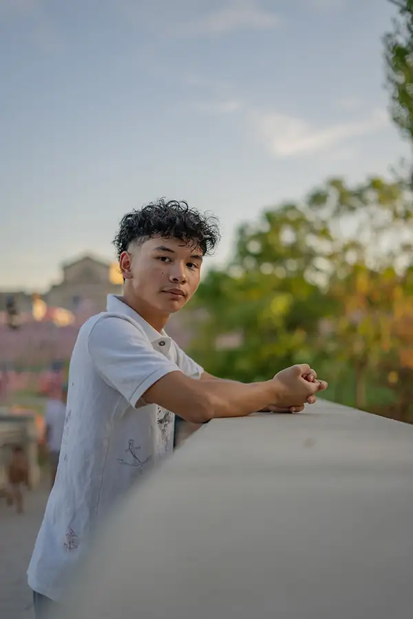 Young man leaning on a stone railing at dusk