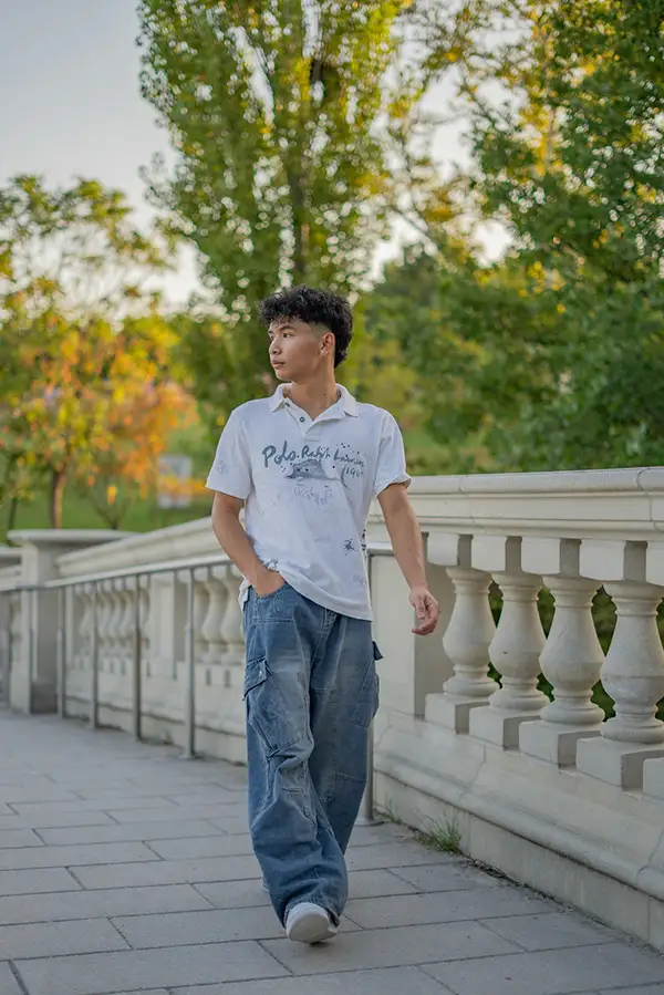 Young man walking across a white stone bridge