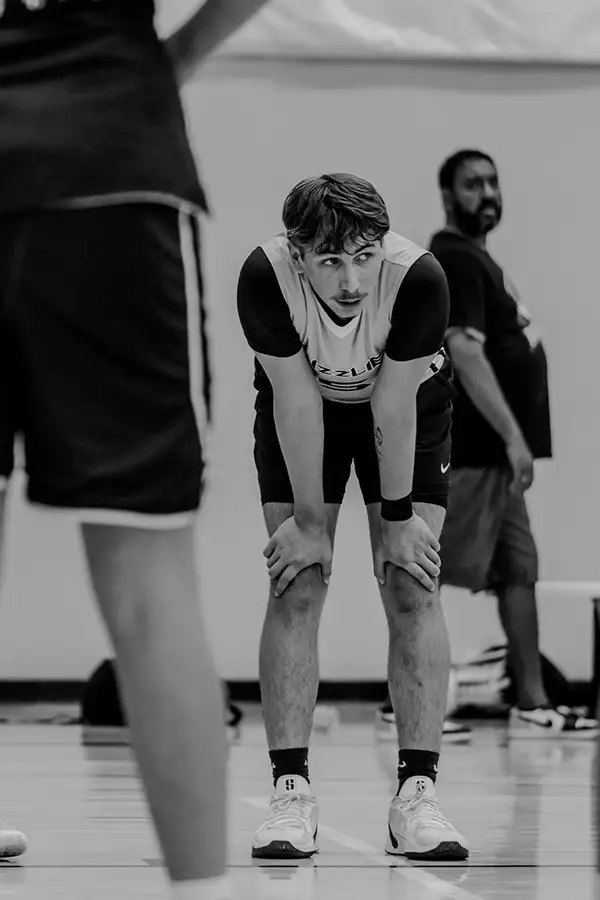 Black-and-white shot of a basketball player resting hands on knees
