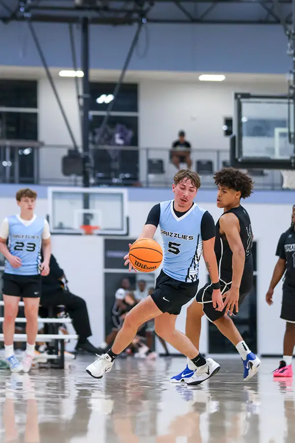 Basketball player driving with the ball in a bright gym