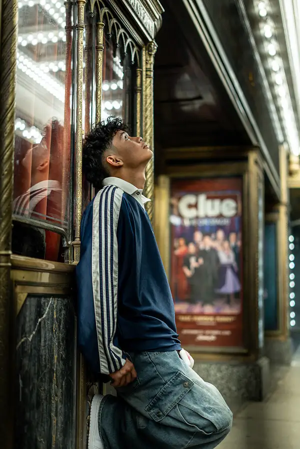 Young man leaning against a theater entrance, looking up