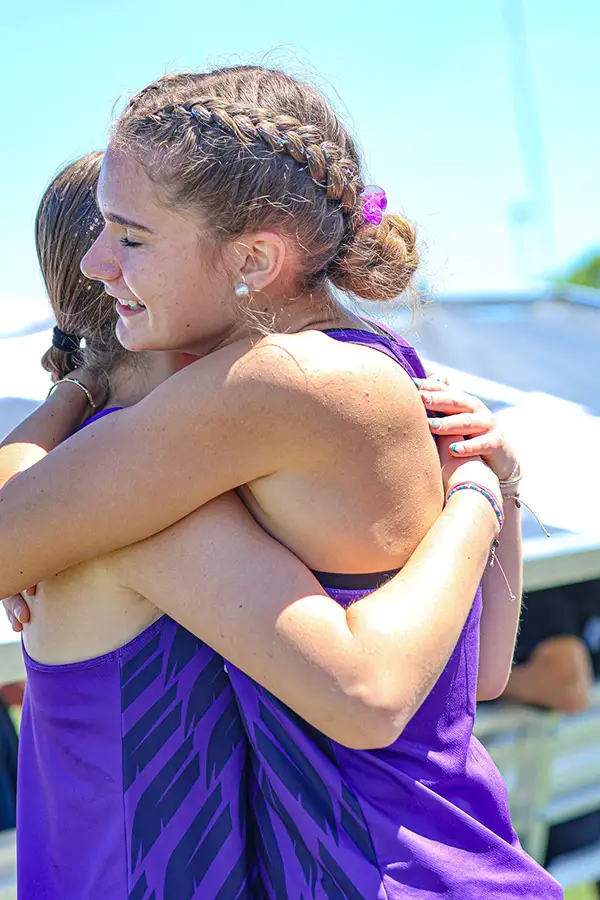 Two teammates in purple hugging after a race