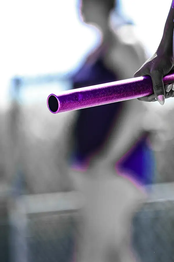 Close-up of a purple relay baton changing hands