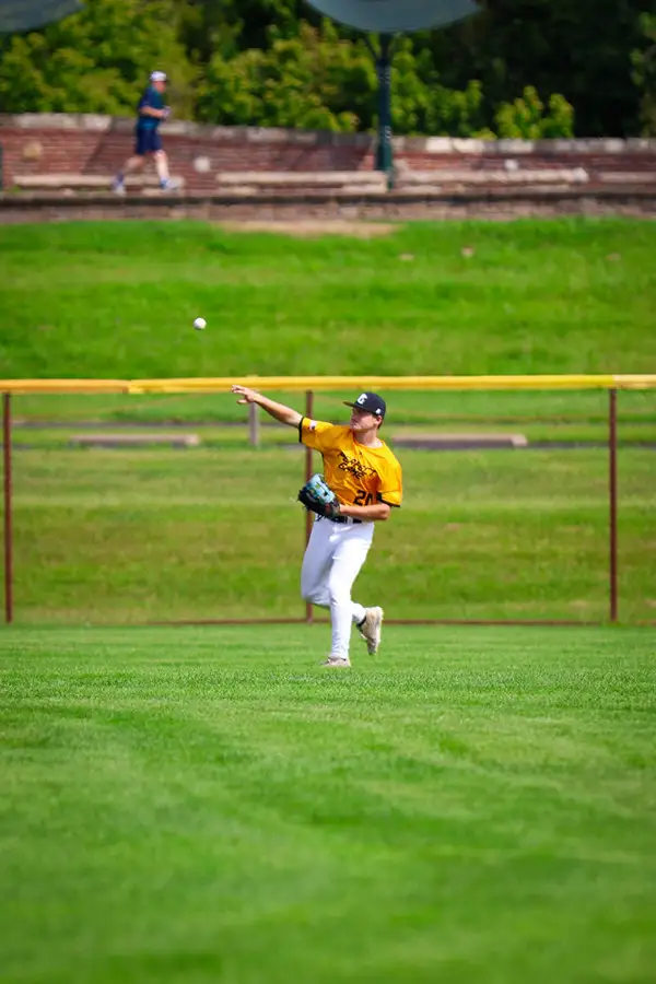 Outfielder in a yellow jersey making a catch on a green field