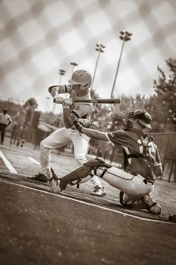 Sepia shot of a batter swinging as the catcher reaches