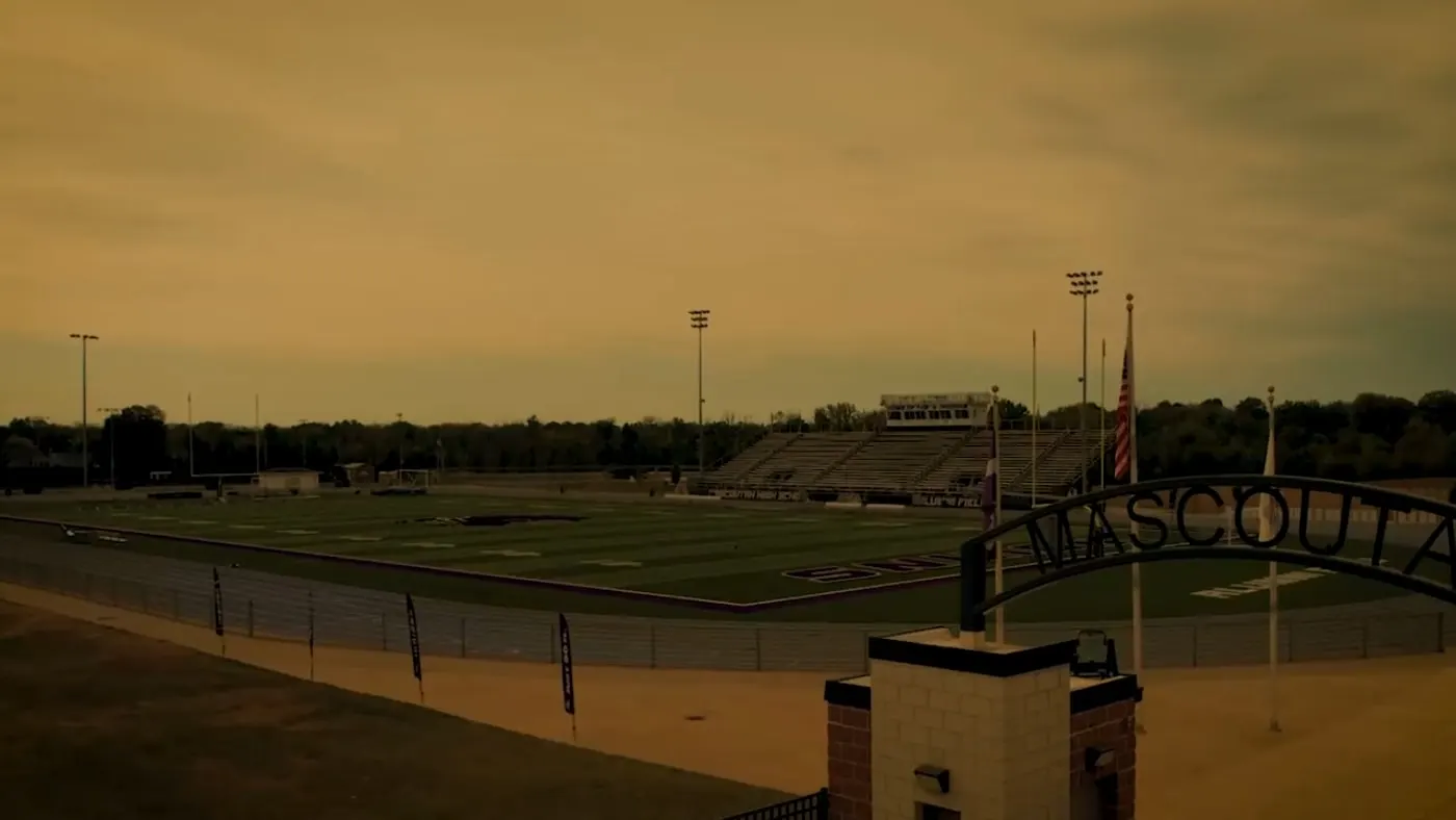 Title card over Mascoutah's stadium under a hazy sky